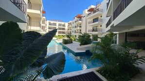Ein Innenhof mit Swimmingpool, umgeben von mehrstöckigen Gebäuden mit Balkonen.