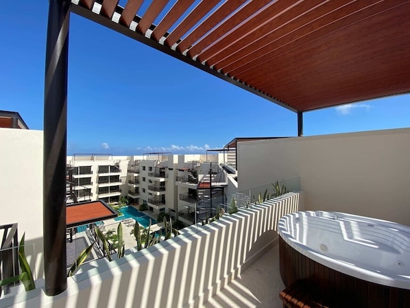 Ein Balkon mit Whirlpool, Pool und Blick auf einen Resortkomplex.