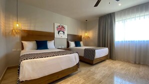 Ein Hotelzimmer mit zwei Betten, einem Deckenventilator, einem Gemälde und einem großen Fenster mit Vorhängen.