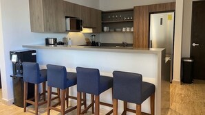 Eine moderne Küche mit Barbereich, Holzschränken und einem Edelstahlkühlschrank.