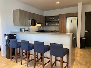 Eine moderne Küche mit Barbereich, Holzschränken und einem Edelstahlkühlschrank.