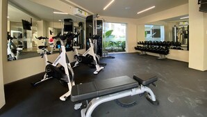 Ein Fitnessstudio mit Trainingsgeräten, Spiegeln und einer Sitzbank.