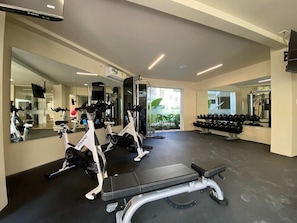 Ein Fitnessstudio mit Trainingsgeräten, Spiegeln und einer Sitzbank.