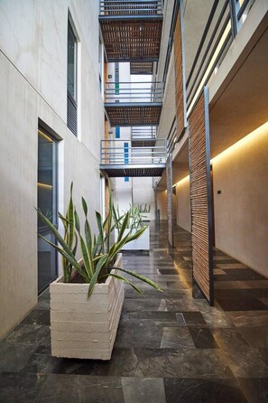 Ein modernes Interieur mit einem zentralen Blumentopf, einer Treppe und einem Korridor mit einem gemusterten Boden.