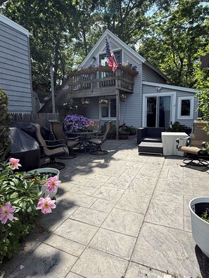 Un patio con mobiliario exterior, una parrilla y plantas en macetas.