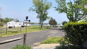 A campground with a paved path, wooden fence, and a weather vane. - Cozy 2-bedroom waterfront cottage with central AC, patio, BBQ, Private beach (Hampton Bays)