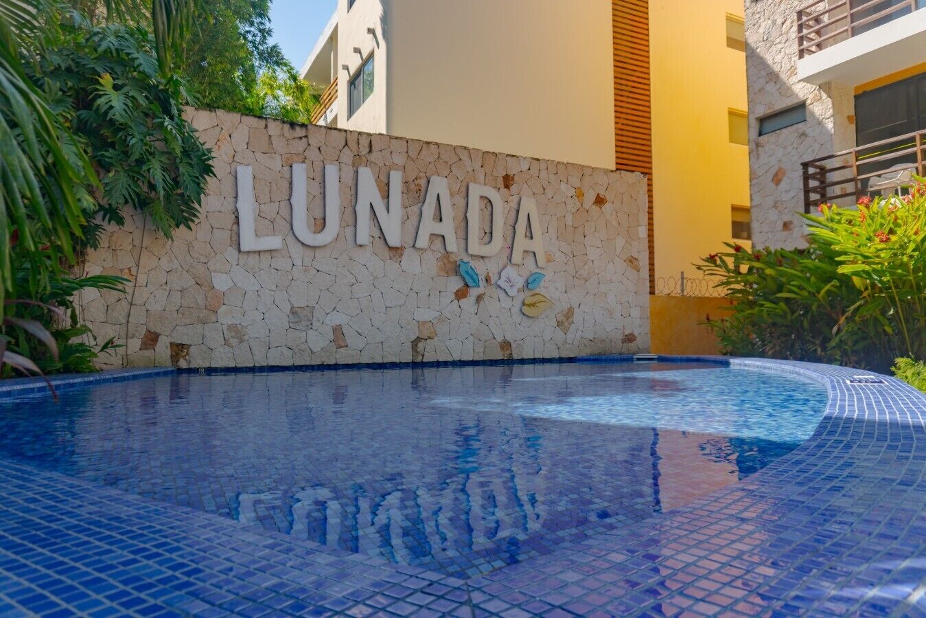 Une piscine avec un mur en pierre et le mot « LUNADA » écrit en grandes lettres.