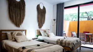 A hotel room with two beds, a small table, a chair, and a balcony with a view. - Lunada: Bright Stay with Rooftop Amenities (Playa del Carmen)