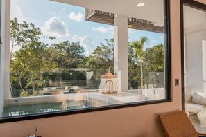 Una habitación moderna con un ventanal grande, una piscina y un pequeño pabellón.
