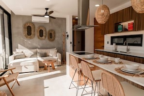 Une cuisine moderne dotée d’un îlot central, de tabourets de bar et d’un coin repas comprenant un canapé et une table basse.