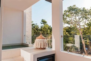 Une salle de bain moderne avec une grande fenêtre, une baignoire et un objet décoratif en macramé posé sur le comptoir.