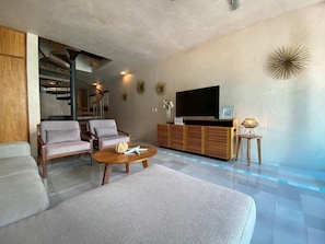 Ein modernes Wohnzimmer mit Treppe, Flachbildfernseher und Poolbereich.