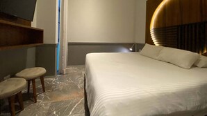 Ein Hotelzimmer mit Bett, Fernseher und einer kleinen Sitzecke.