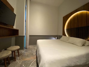 A hotel room with a bed, a TV, and a small seating area. - Joy: Apt with rooftop and panoramic views (Playa del Carmen)