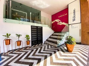A modern lobby with a chevron-patterned floor, a staircase, and a 'Welcome' sign. - Joy: Apt with rooftop and panoramic views (Playa del Carmen)