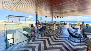 Ein moderner Außenbereich mit Sitzgelegenheiten und Glasbrüstung, mit Blick auf den Strand.
