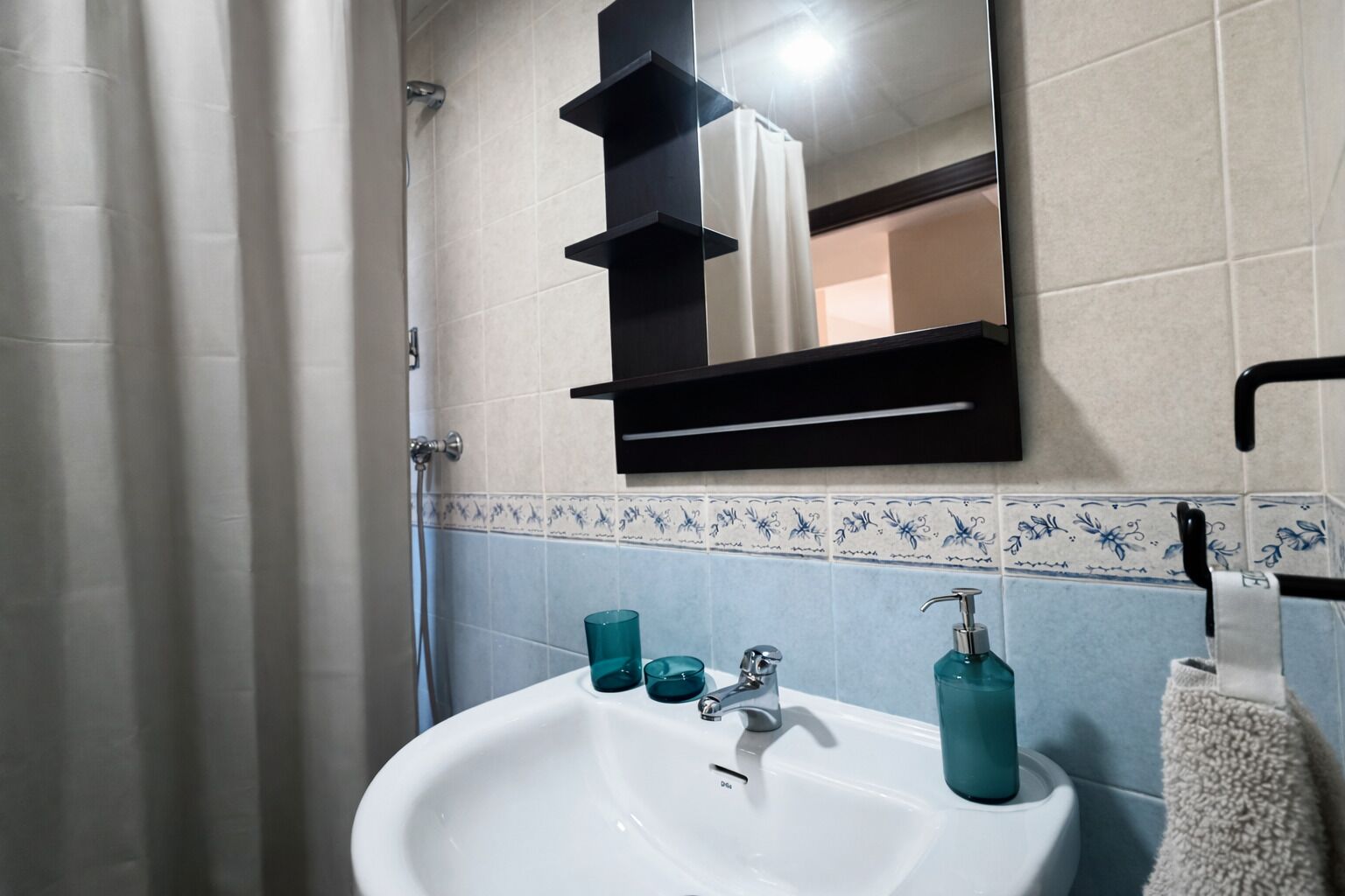 A bathroom with a white sink, a mirror, a towel rack, and a shower curtain.