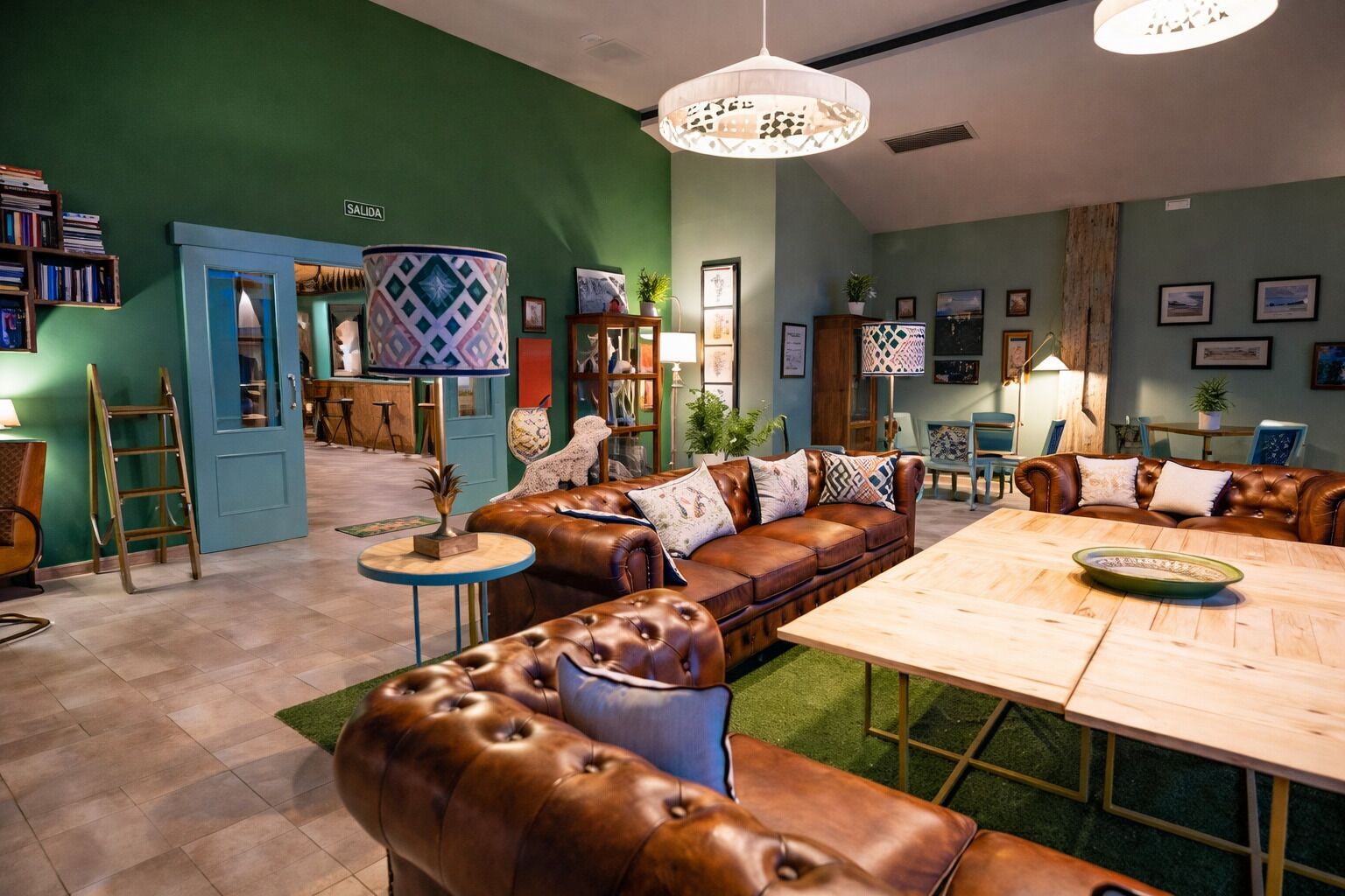 A spacious living area with a large brown leather sofa, a wooden coffee table, and a blue door labeled 'SALIDA'.