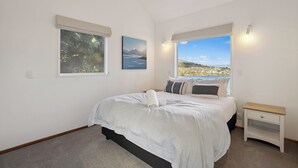 Un dormitorio con cama, mesita de noche, ventana con vistas y dos cuadros en la pared.
