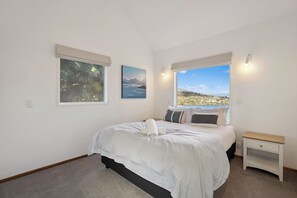 Ein Schlafzimmer mit Bett, Nachttisch, Fenster mit Blick und zwei Wandbildern.