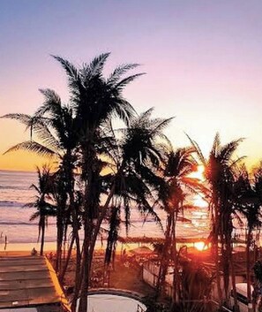 Sonnenuntergang mit Palmen und Strand.