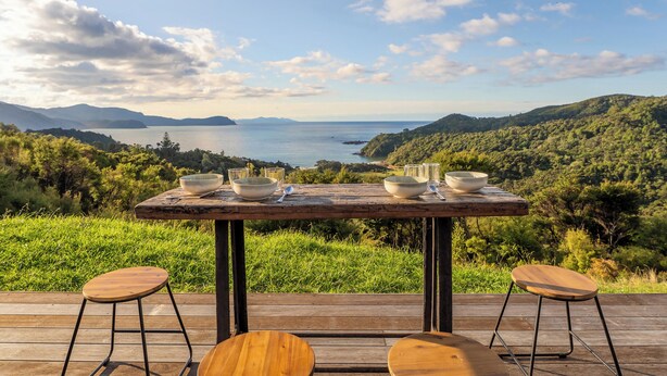 Ein Holztisch mit Schalen und Gläsern auf einer Terrasse mit Blick auf eine malerische Landschaft.