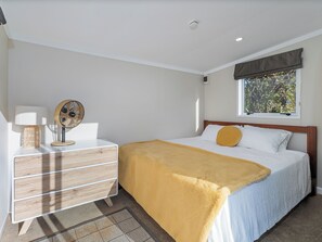 Ein Schlafzimmer mit Bett, Nachttisch, Lampe und Fenster.