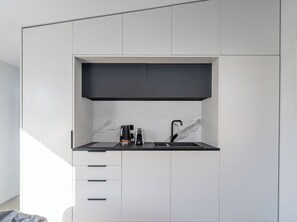 Eine moderne Küche mit schwarzem Arbeitsplatz, einer Kaffeemaschine, einem Spülbecken und einer Marmor-Spritzschutzwand.