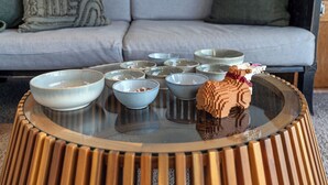 Ein modernes Wohnzimmer mit einem runden Glastisch, einer grauen Couch und dekorativen Kissen.