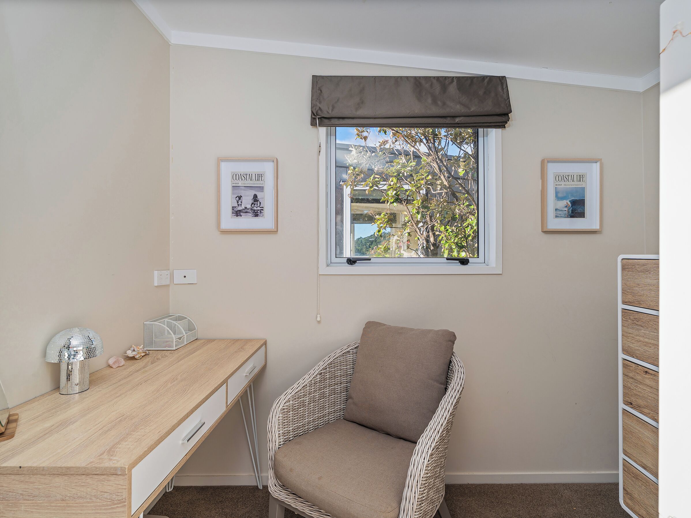 A room with a desk, chair, framed pictures, and a window with a view.