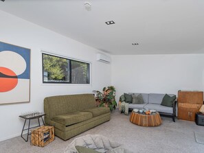 Ein modernes Wohnzimmer mit einem grünen Sofa, einem grauen Couch und einer Holzkabine.