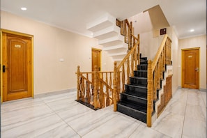 A hotel interior with a wooden staircase, marble flooring, and wooden doors. - Deluxe Pine Hills (Srinagar)