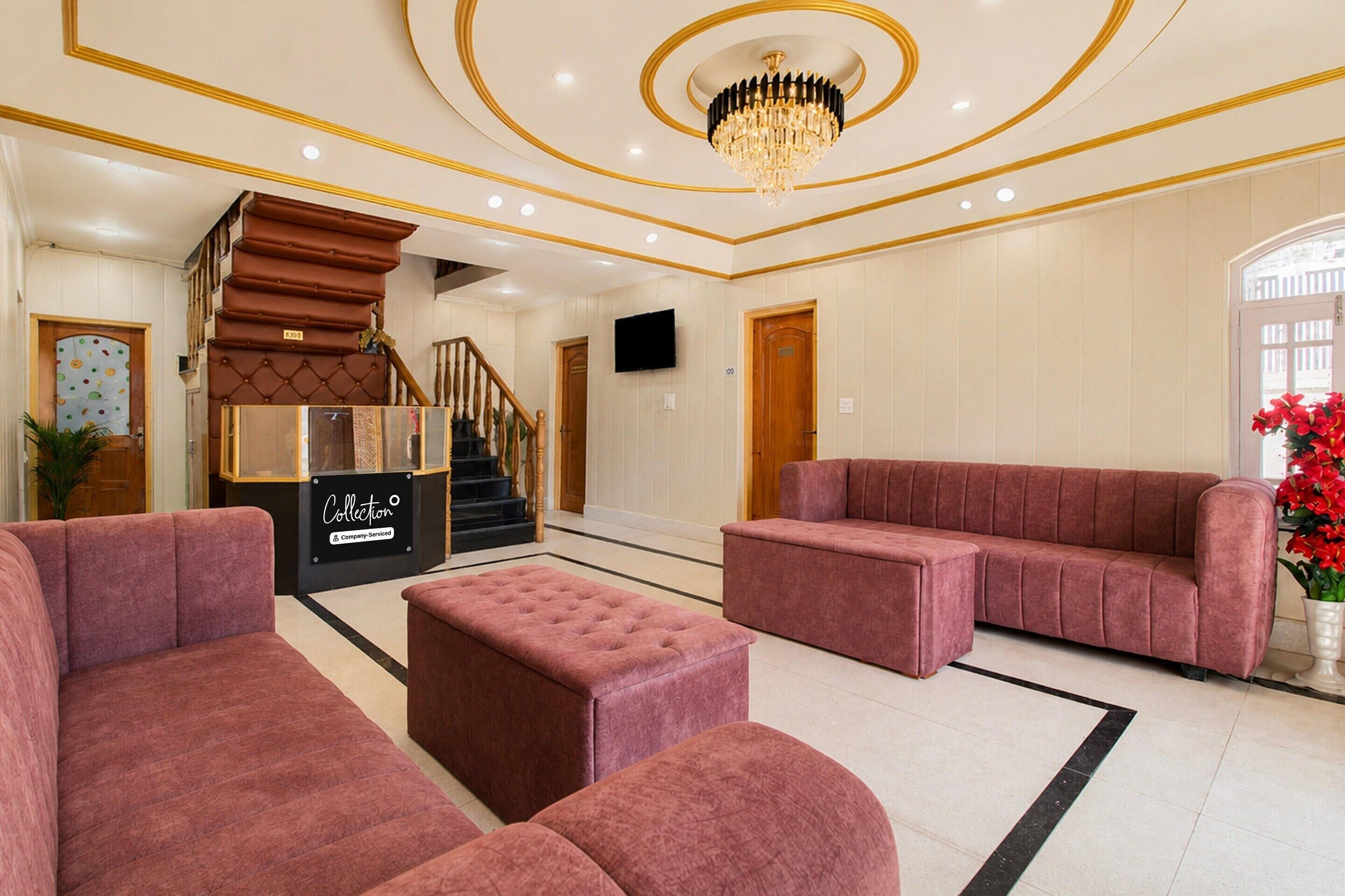 A spacious lobby with a grand staircase, plush seating, and a chandelier.