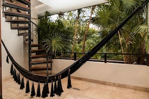 A staircase with a black railing, a hammock, and lush tropical plants. - Bajo Cielo: Jungle-View Terrace with Private Pool (Tulum)