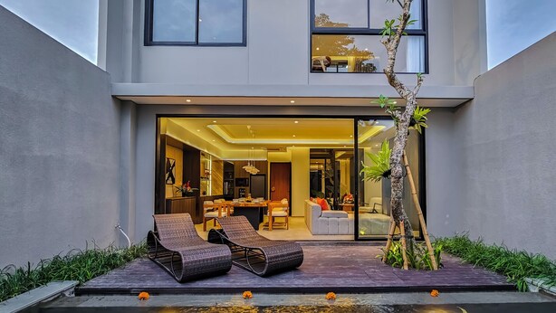Ein modernes Haus mit Pool, Liegestühlen und Essbereich.