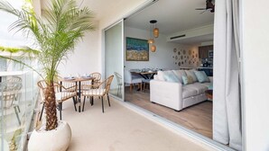 A balcony with a palm tree, wicker chairs, and a dining table. - Stylish Apt with Private Balcony, Pool and Gym (Playa del Carmen)