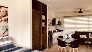Eine moderne Wohnung mit Essbereich, Küchenzeile und einem Bett mit gestreifter Bettwäsche.