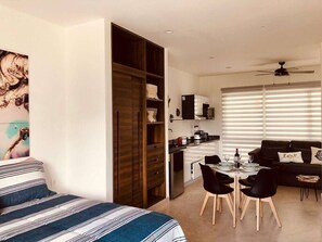 Eine moderne Wohnung mit Essbereich, Küchenzeile und einem Bett mit gestreifter Bettwäsche.