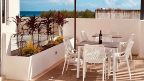 Eine Terrasse mit Tisch, Stühlen und einem roten Sonnenschirm.