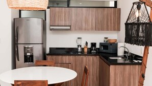 Ett modernt kök med inbyggt kylskåp, mikrovågsugn, kaffebryggare och en hängande lampa.