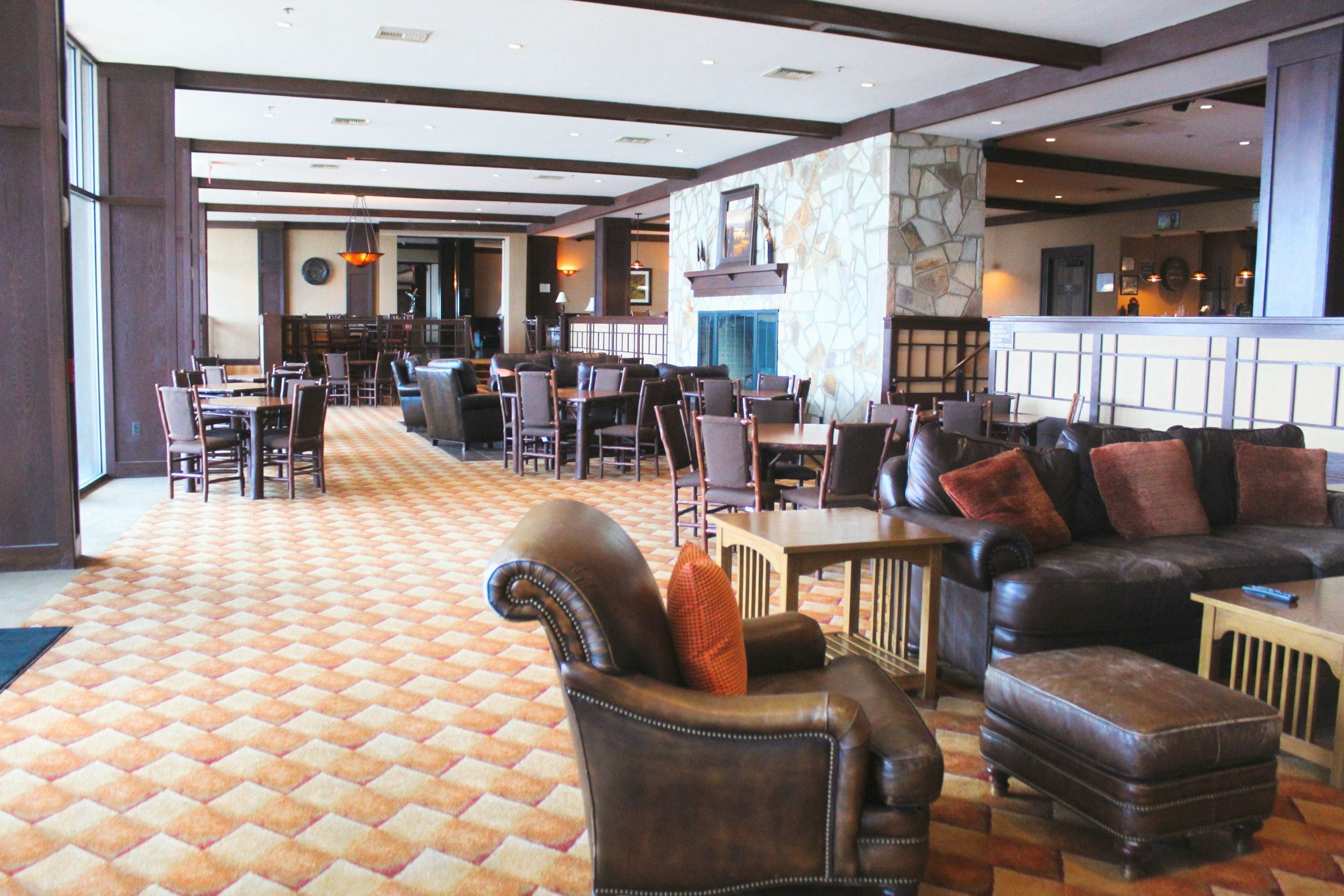 A spacious lobby with a checkered carpet, leather seating, a fireplace, and a bar area.