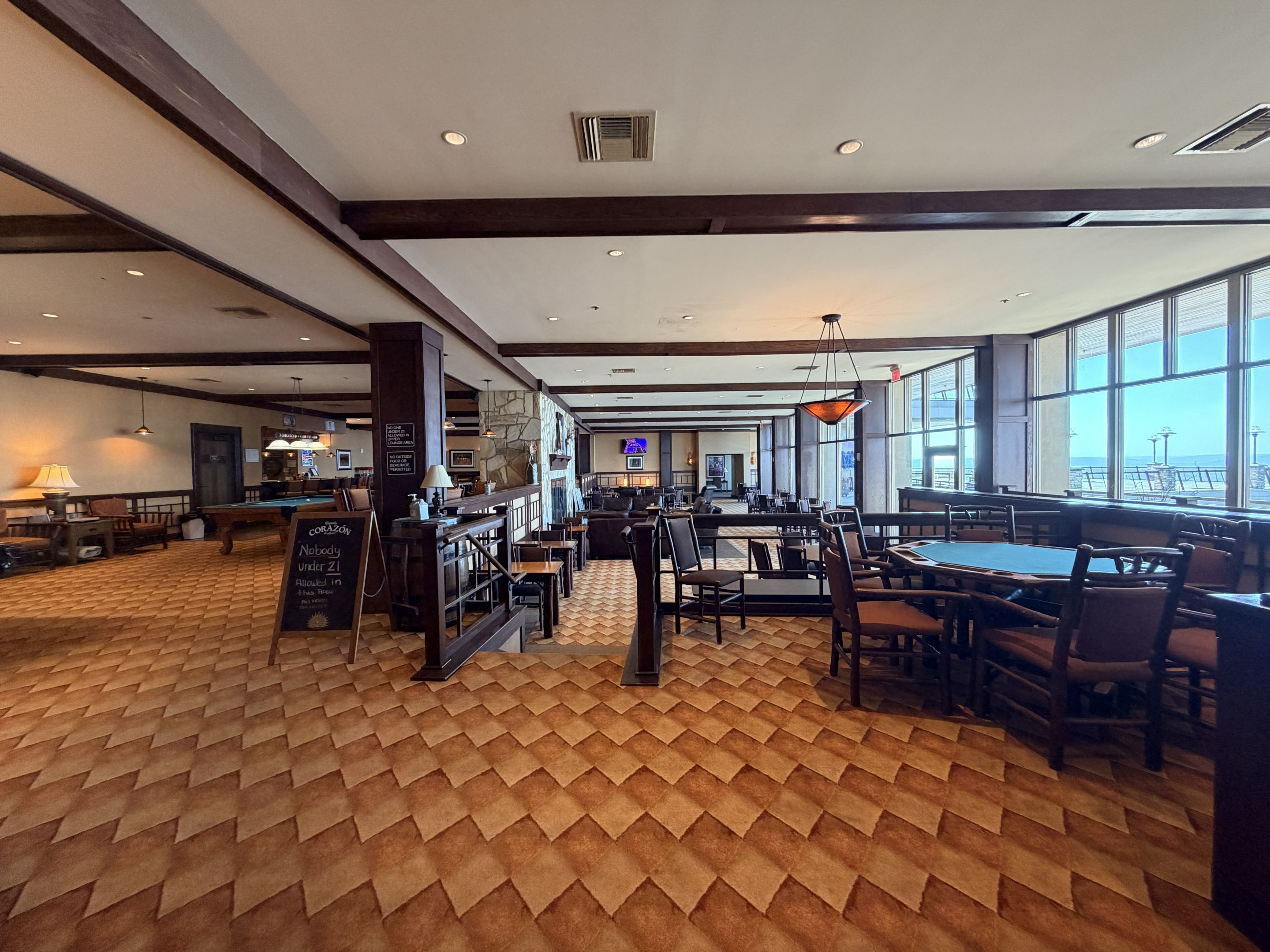 A spacious indoor area with a pool table, multiple seating arrangements, and large windows offering views.