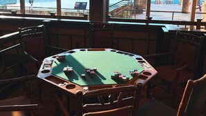 A pool table with chips and a view of the sea through large windows.