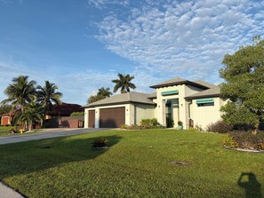 Une maison d’habitation avec un garage, une pelouse bien entretenue et des palmiers.