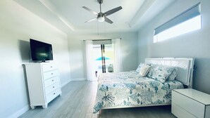 A bedroom with a bed, a TV, a ceiling fan, a dresser, and a window. - Gorgeous 3-bedroom house with Heated Pool and Spa (Cape Coral)