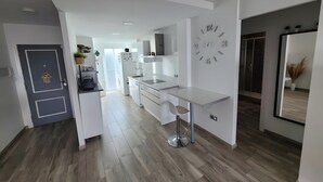 A modern kitchen with white cabinetry, a built-in oven, and a wall clock.