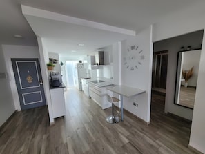 Een moderne keuken met witte kasten, een inbouwoven en een wandklok.