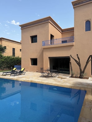 A poolside area with lounge chairs, a table, and a covered seating area. - Villa Zitouna Luxury Golf & Pool & Garden Amelkis (Marrakech)