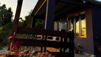 A modern building with a wooden deck, a glass door, and a string of lights.