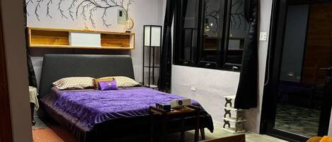 A modern bedroom with a bed, bedside table, lamp, and a view of the outside.
